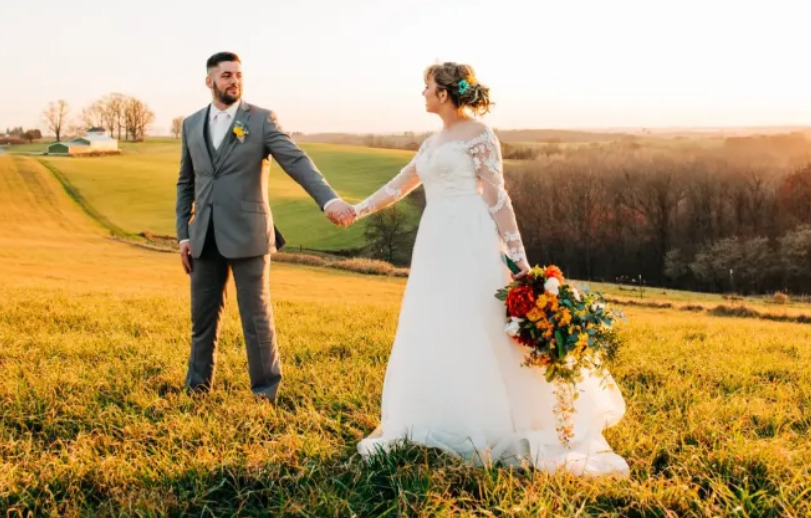 Steph and Ben hold hands in a field